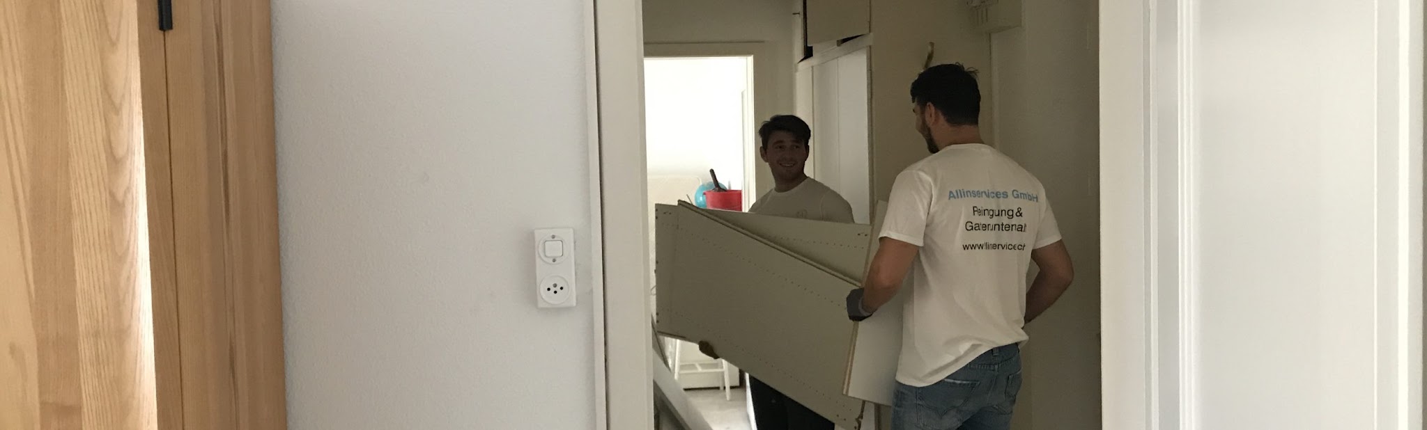 Zwei Mitarbeiter tragen ein Möbelstück durch eine Wohnung