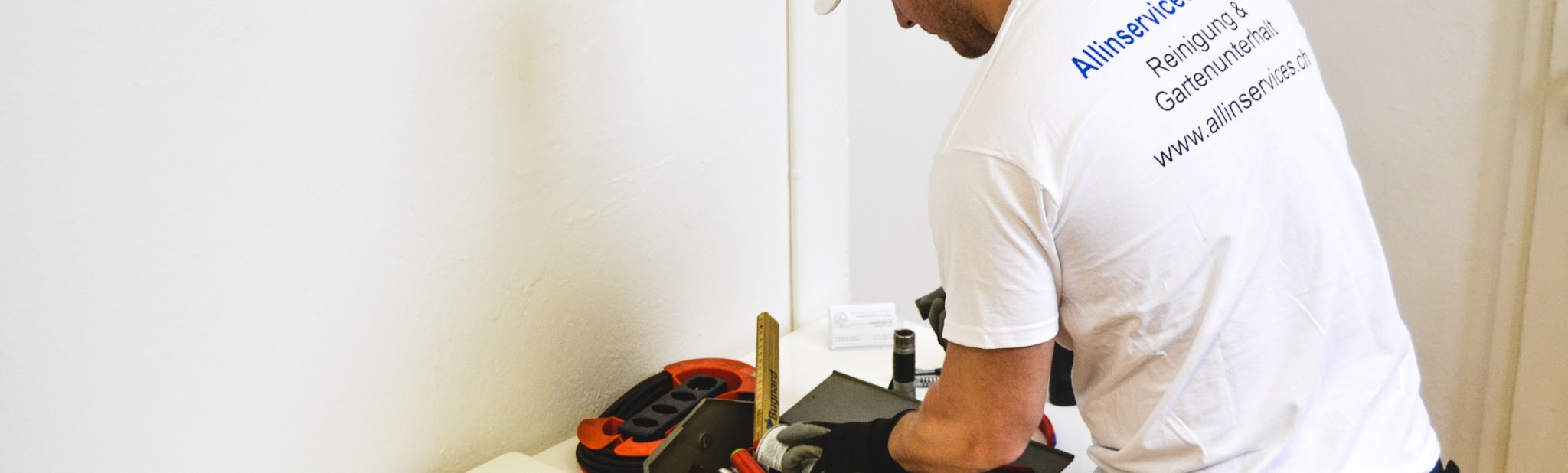 Mitarbeiter im Firmenshirt bei Arbeiten an einer Fensterbank