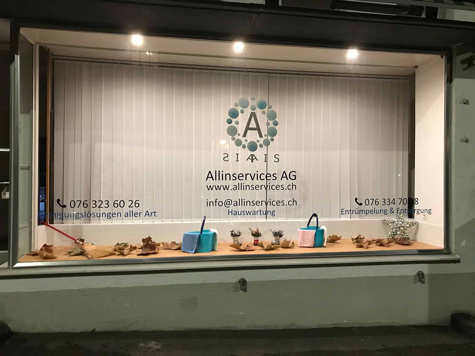 Schaufenster der Allinservices AG an der Altstetterstrasse 288 mit Logo, Telefonnummern und Reinigungseimern